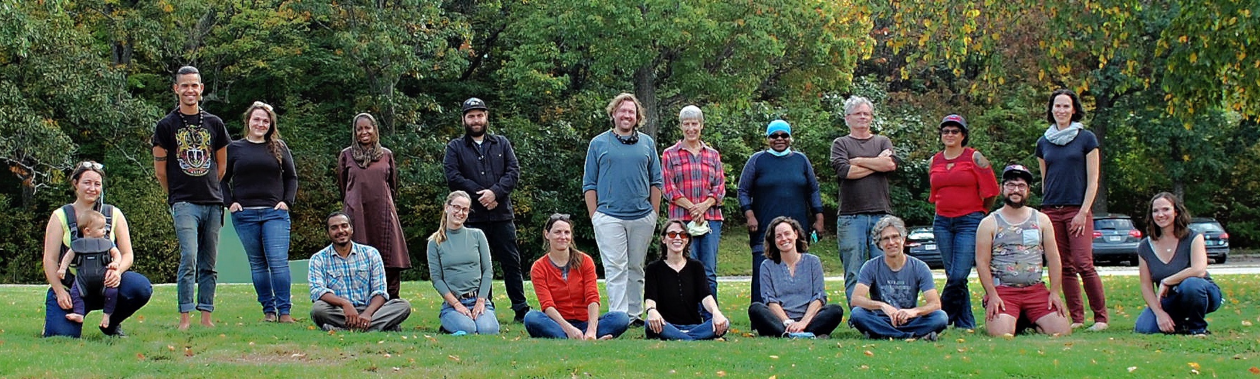 A group of about 20 people standing and sitting in a field for a photo